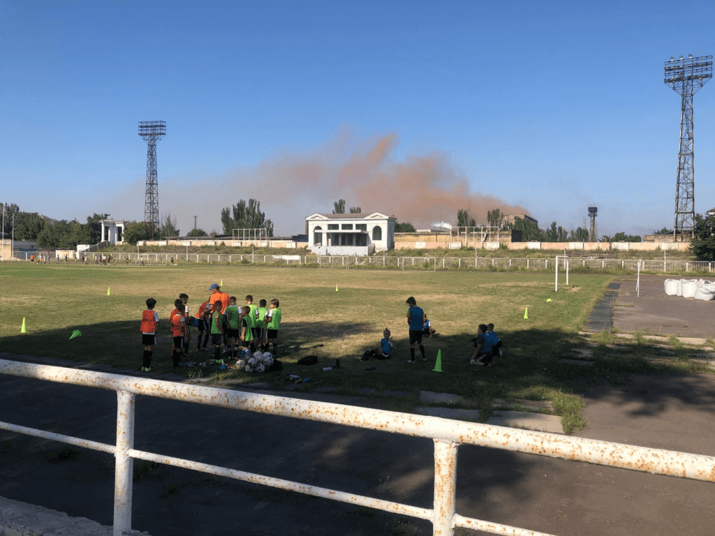 Дети готовятся к тренировке. На фоне — бурое облако выбросов меткомбината