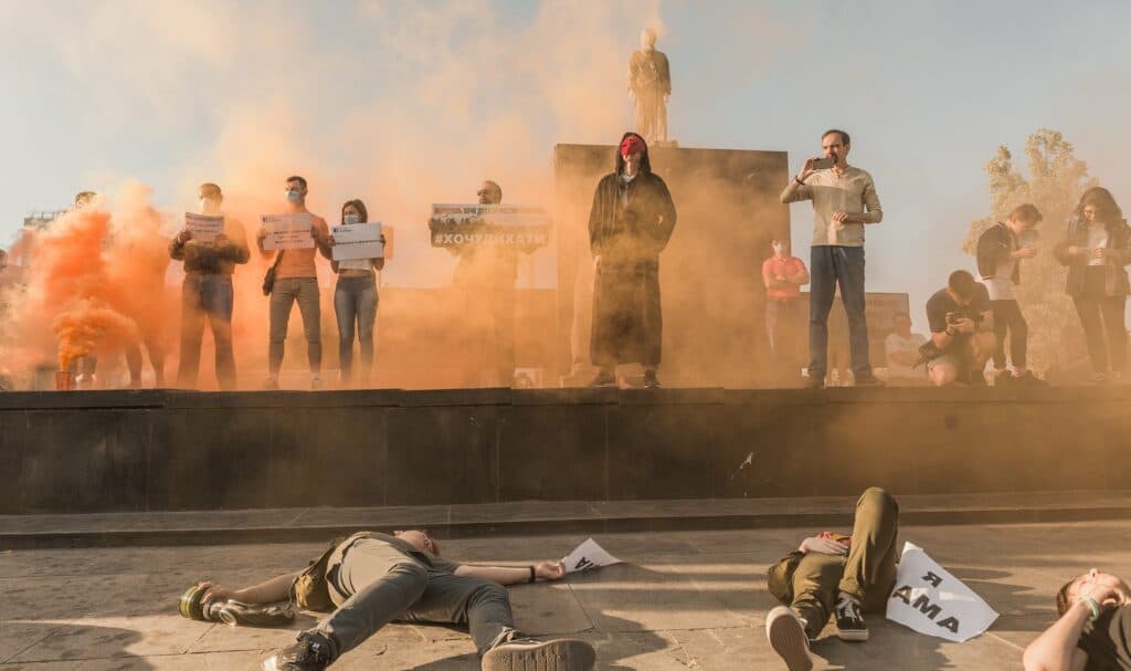 Во время митинга актеры представили перформанс, упав замертво, будто отравились оранжевым дымом