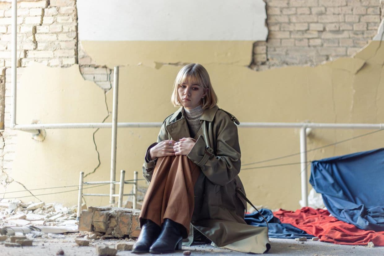<em>Дівчина сидить у розбитій будівлі. Фото ілюстративне: Freepik</em>