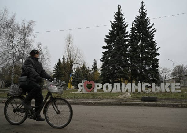 Чоловік проїжджає на велосипеді повз знак "Я люблю Родинське" порожньою вулицею в місті Родинське, 16 січня 2025 року. Фото: GENYA SAVILOV/AFP via Getty Images